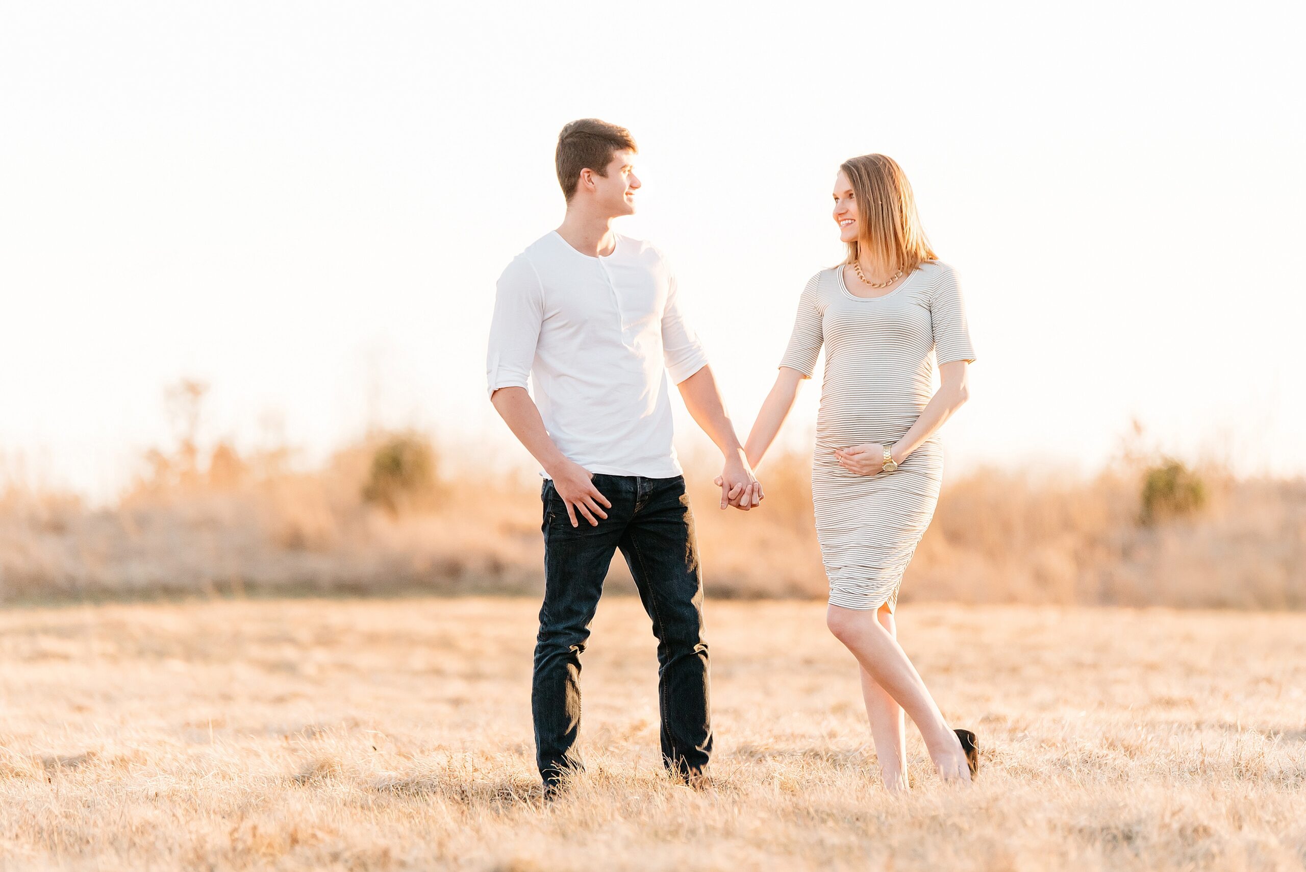 golden hour maternity photo of couple looking at each other